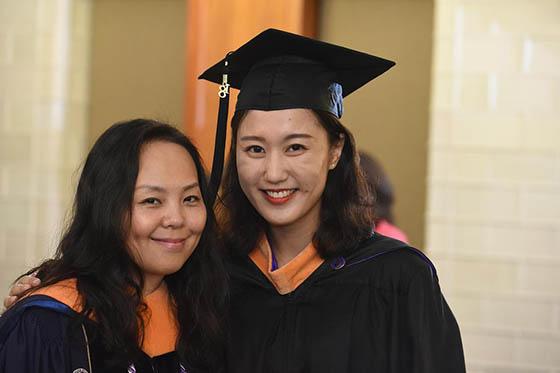 两名年轻女子戴着毕业帽，身穿毕业服，在镜头前摆姿势
