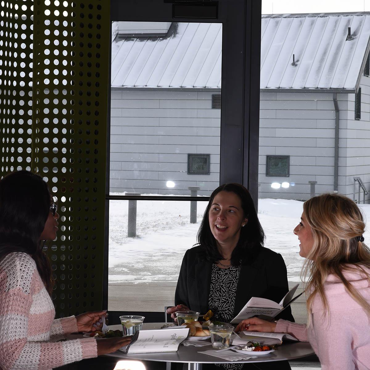 图为一群妇女坐在伊甸大厅校园的一张桌子上，一起谈笑