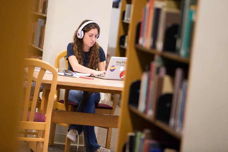 图为一名波胆网站的学生在图书馆的电脑前工作.